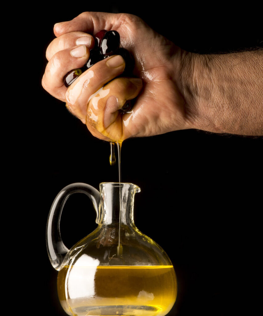 Hand squeezing oil from olives