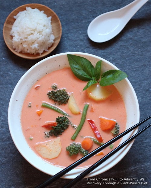 Thai Red Curry served in a bowl with chopsticks and rice on the side