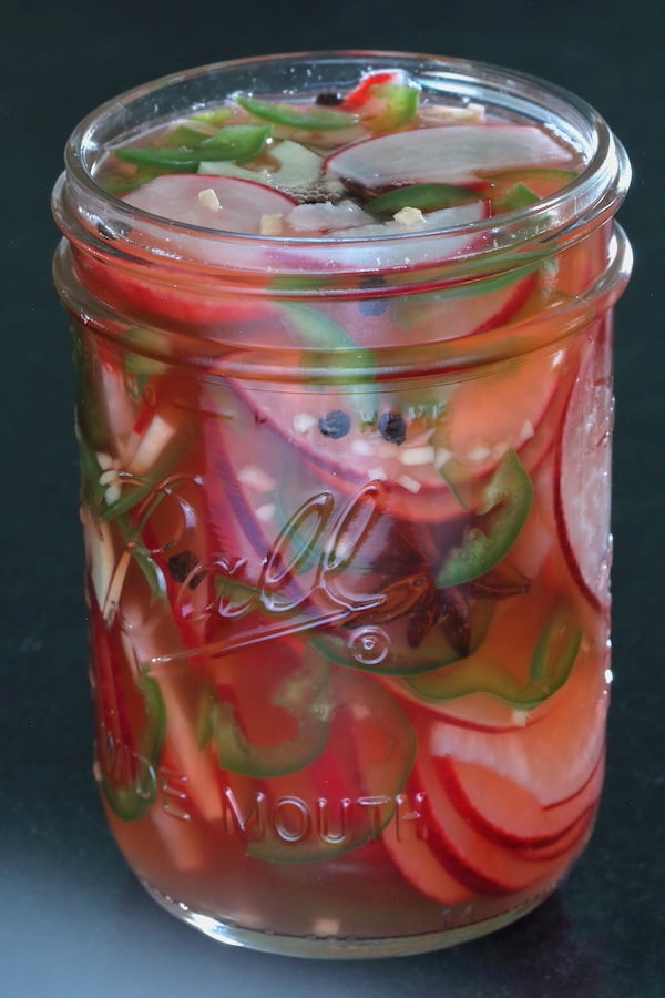 Side view of a pint-sized jar of Spicy Pickled Radishes with Jalapeños