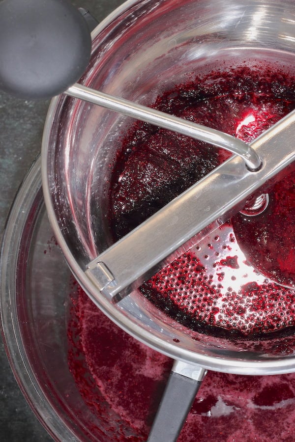 Blueberry seeds being removed from blueberry puree using a food mill