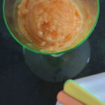 A scoop of peach sorbet in a pale green stemmed glass