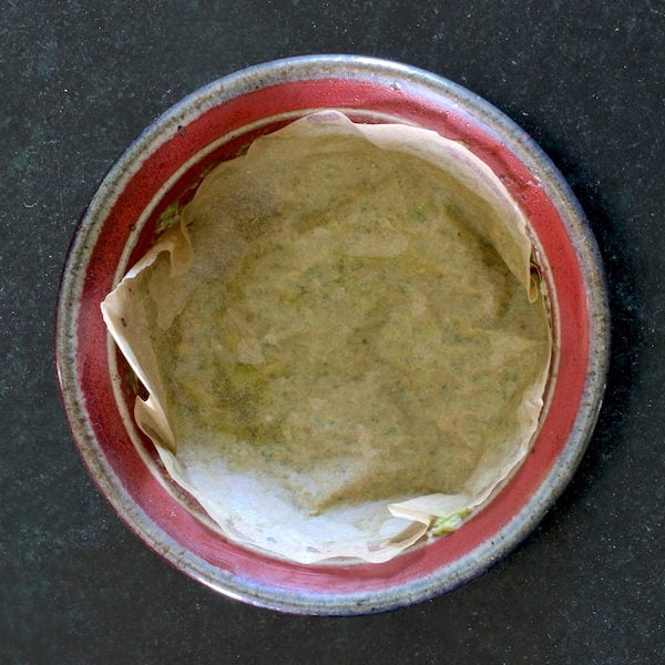 Oil free vegan pesto leftovers in a small bowl covered with parchment paper.