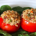 Four quinoa stuffed tomatoes on a bed of spinach