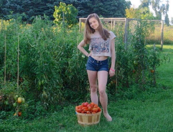 Our daughter Laura standing in front of our tomato garden with a basket of picked tomatoes