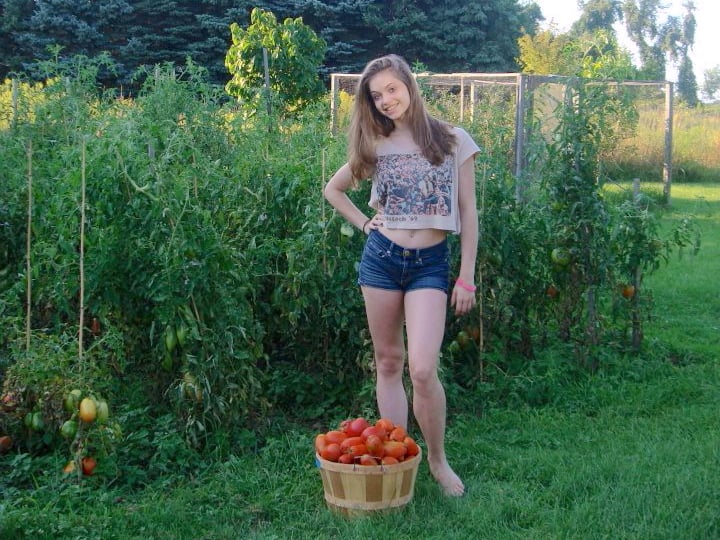 Our daughter Laura standing in front of our tomato garden with a basket of picked tomatoes