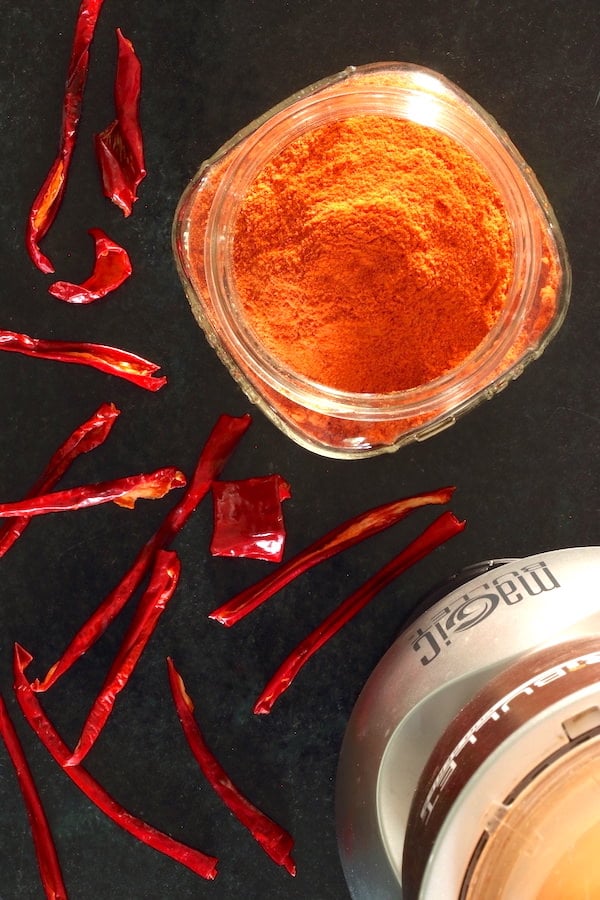 Ground paprika in a jar with dried peppers strewn about