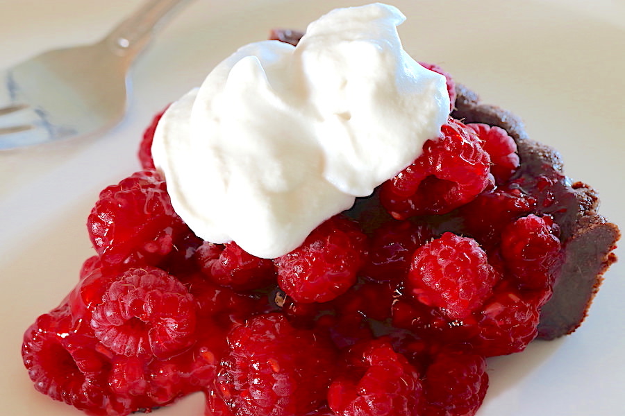 A slice of Fresh Raspberry Tart with whipped cream