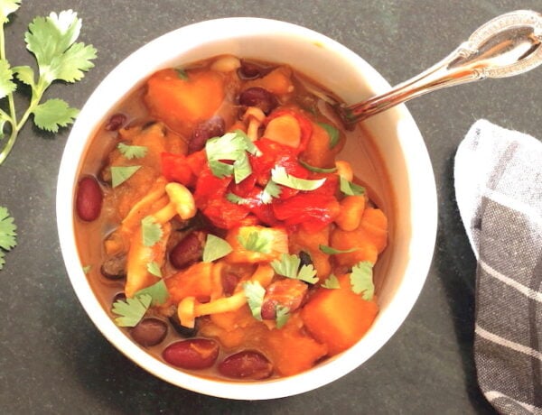 Butternut Squash Chili in a bowl with sprig of cilantro t the side