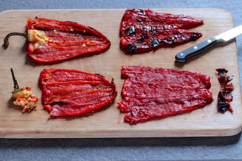 Roasted red peppers with seeds and stems removed laying on cutting board