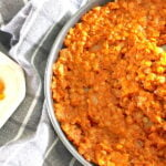 Ethiopian spicy red lentils in skillet with glimpse of Ethiopian cabbage stew