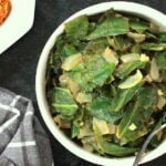 Ethiopian style collard greens in a bowl with a glimpse of spicy lentils to the side