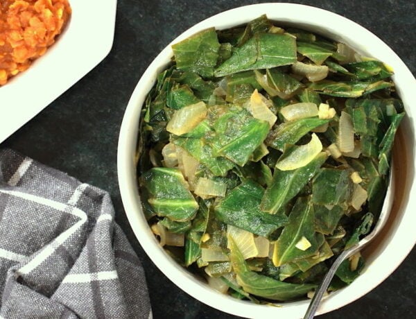 Ethiopian style collard greens in a bowl with a glimpse of spicy lentils to the side