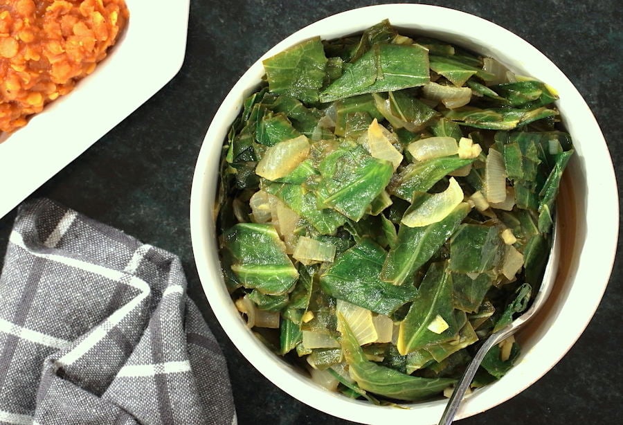 Ethiopian style collard greens in a bowl with a glimpse of spicy lentils to the side