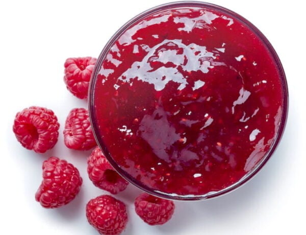 Raspberry Jam in jar with fresh raspberries strewn about