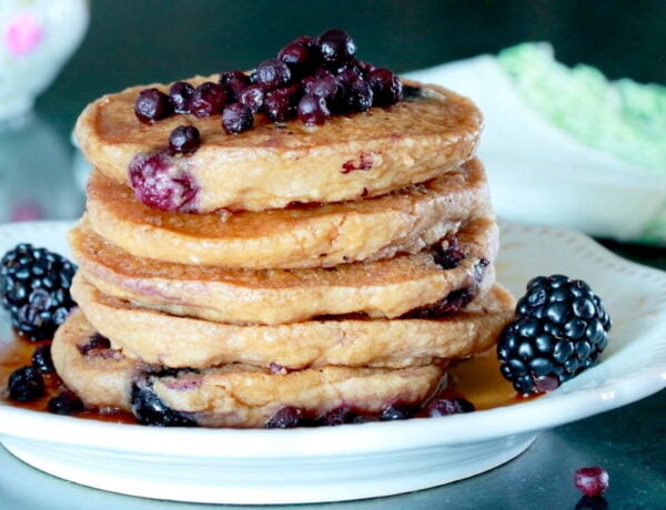Stack of Fluffy Blueberry Oatmeal Pancakes with fresh wild blueberries on top, garnished with fresh blackberries and maple syrup