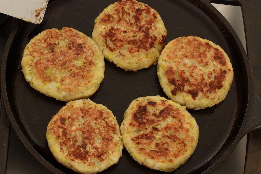 Five Vegan Potato Pancakes with Leeks cooking on cast iron skillet