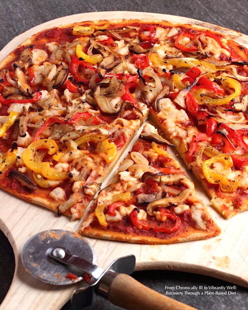 Flatbread pizza cut up on pizza paddle; topped with mushrooms, onion, and peppers