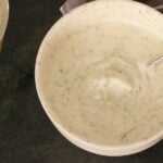 Tzatziki Sauce in a bowl with a glimpse of lemon squeezer and napkin in the background