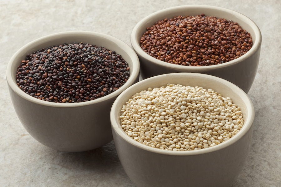 Three bowls containing white, black, and red quinoa