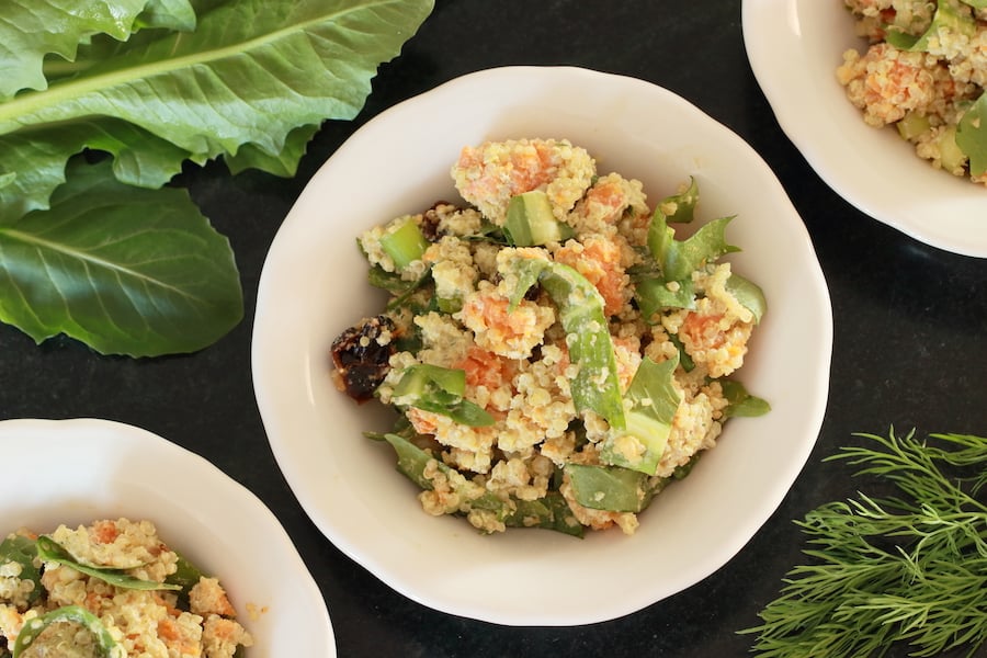 Quinoa Salad served in three side-dish bowls with dandelion greens and fresh dill in the background