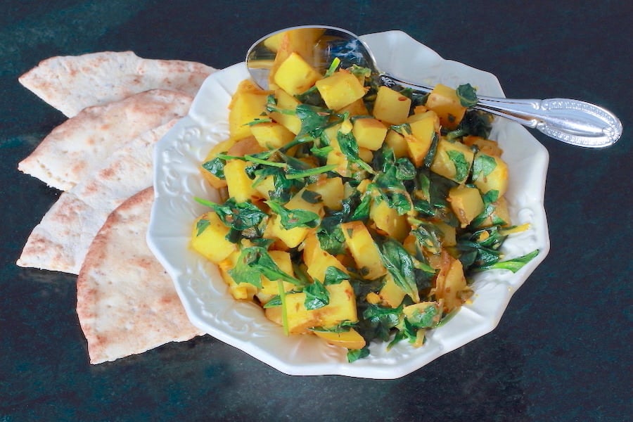 Bowl of Aloo Palak with a cut up flatbread