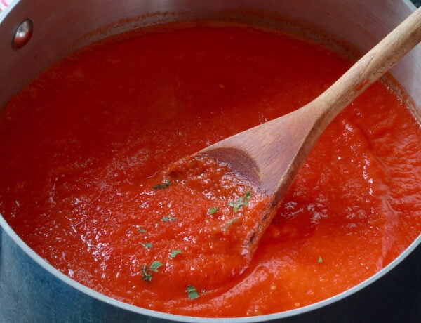A pot of Vegan Pasta Sauce being stirred with a wooden spoon