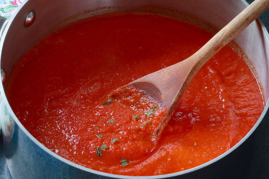 A pot of Vegan Pasta Sauce being stirred with a wooden spoon