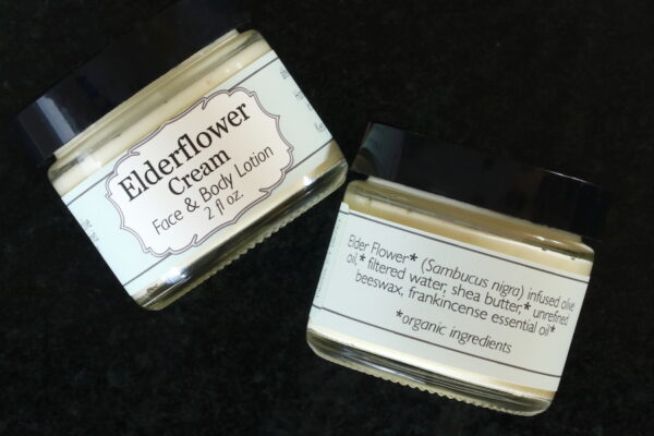 View of front and back labels of open jar of Elderflower Cream